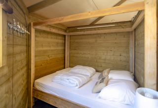 Dormitorio de madera con cama con dosel en Dune house de Marina Parcs Almere, Países Bajos, ambiente acogedor.