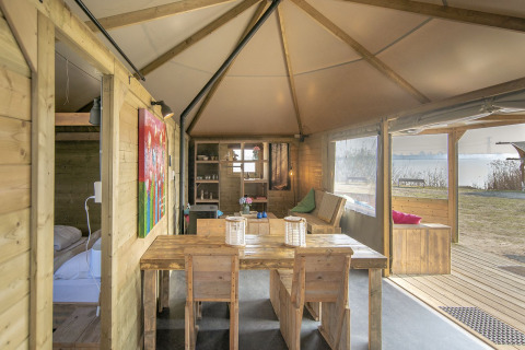Vista interior de la cabaña Dune house en Marina Parcs Almere, Países Bajos, con muebles de madera y lago.
