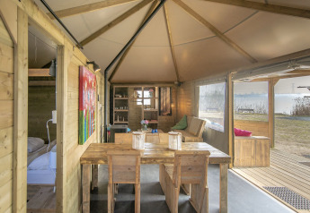 Vista interior de la cabaña Dune house en Marina Parcs Almere, Países Bajos, con muebles de madera y lago.