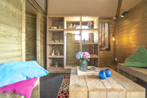 Joli intérieur en bois du Dune house à Marina Parcs Almere, Pays-Bas, avec coussins colorés et fleurs.