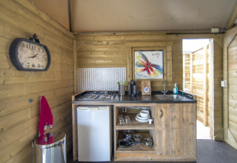 Knus houten keukentje in het Dune House bij Marina Parcs Almere, met fornuis, koelkast en kleurrijke decoratie.