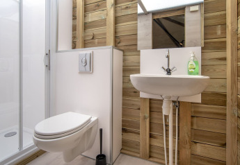 Modern bathroom with wooden walls, wall-mounted toilet, sink, and shower in Dune house at Marina Parcs Almere.