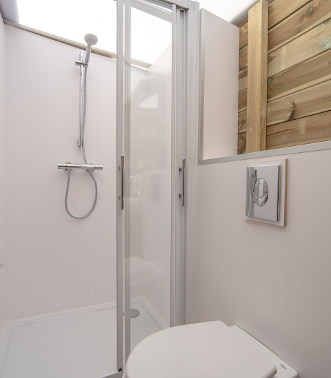 Douche et toilettes modernes au Dune House de Marina Parcs Almere, Pays-Bas, avec mur en bois et porte vitrée.
