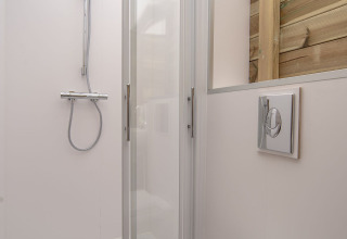 Ducha y baño modernos en Dune House de Marina Parcs Almere, Países Bajos, con pared de madera y puerta de vidrio.