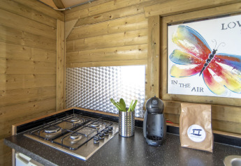 Køkkenområde i Dune House, Marina Parcs Almere, med gaskomfur, kaffemaskine og farverig sommerfuglkunst.