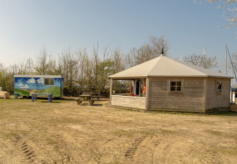 Foto della lodge Dune House a Marina Parcs Almere, Paesi Bassi, con capanna in legno e tavoli da picnic.