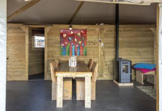 Binnenzicht van Dune House bij Marina Parcs Almere met houten meubels, kleurrijk schilderij en kachel.