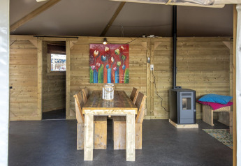 Intérieur du Dune House à Marina Parcs Almere avec meubles en bois, tableau et poêle à bois.