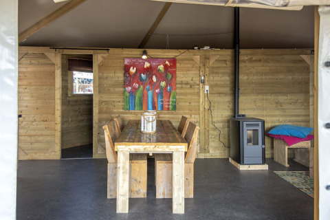 Binnenzicht van Dune House bij Marina Parcs Almere met houten meubels, kleurrijk schilderij en kachel.