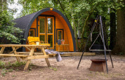 Acogedora tiny house amarilla con banco al aire libre y área de fogata en Buitengoed Ruysbos, Países Bajos.