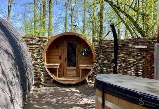 Outdoor wellness area with barrel sauna and hot tub at Boshuys Ultra Wellness tiny house in Buitengoed Ruysbos, Netherlands.