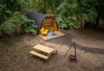 Tiny house Boshuys Ultra Wellness al Buitengoed Ruysbos nei Paesi Bassi, circondata da alberi e arredo da esterno.