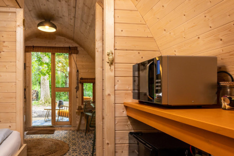 Interior de una tiny house con paredes de madera, microondas y vista al jardín en los Países Bajos.