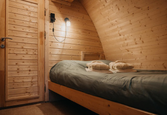 Accogliente camera da letto nella tiny house Boshuys Ultra Wellness a Buitengoed Ruysbos, Paesi Bassi, con pareti in legno.