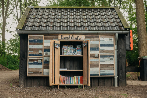 Et lille træhus med et skilt 'Brood/Info', omgivet af skov, set ved Buitengoed Ruysbos, Holland.