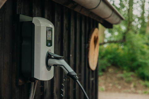 Laadpunt voor elektrische auto aan de muur bij Boshuys Ultra Wellness, Buitengoed Ruysbos, Nederland.