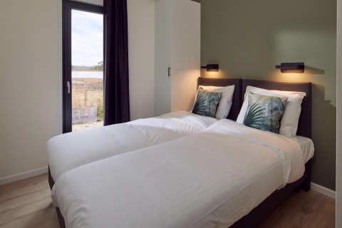 Dormitorio moderno en Holiday villa Amalia 6 + sauna en Hofparken De Bergvennen, con dos camas individuales.