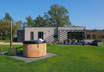 Moderne feriebolig med udendørs spabad, græsplæne og terrasse ved Hofparken De Bergvennen, Holland.