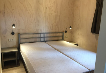 Slaapkamer in een Safarilodge-tent op Camping de Noetselerberg met twee eenpersoonsbedden en houten muren.