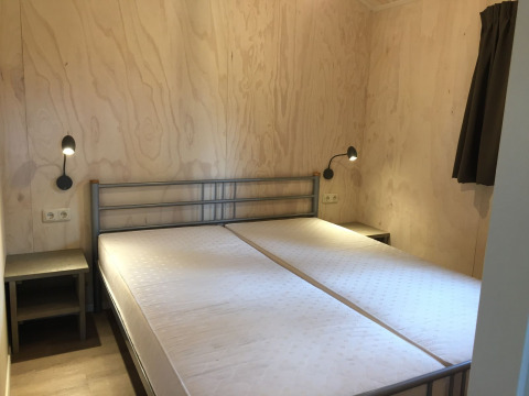 Camera da letto nella tenda Safarilodge al Camping the Noetselerberg con due letti singoli e pareti in legno.