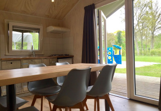 Interiør af Safarilodge i Camping de Noetselerberg, Holland, med udsigt til legeplads gennem åben dør.