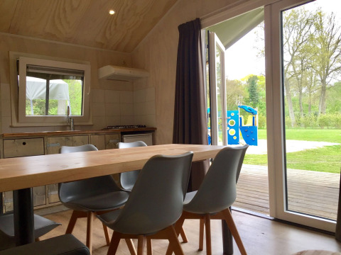 Interiør af Safarilodge i Camping de Noetselerberg, Holland, med udsigt til legeplads gennem åben dør.