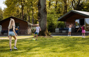 Børn leger udenfor Safarilodge-safaritelte på Camping Noetselerberg, Holland, en solrig dag.