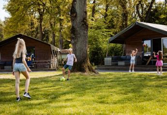 Children playing outside safari tents at Safarilodge, Camping the Noetselerberg, Netherlands, sunny day.