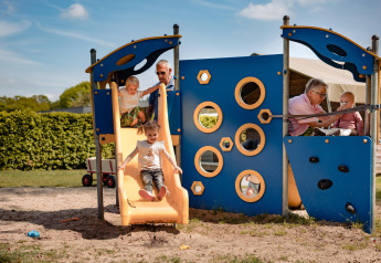 Kinderen spelen op een speelplaats bij Safarilodge, Camping de Noetselerberg, Nederland, met volwassenen.