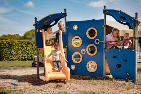 Bambini giocano su un parco giochi a Safarilodge, Camping the Noetselerberg, Paesi Bassi, insieme ad adulti.