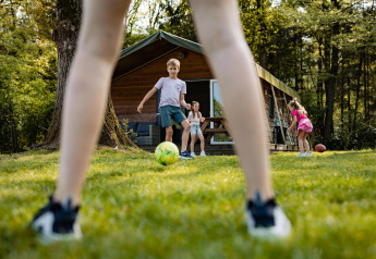 Bambini che giocano a calcio davanti a una tenda safarilodge al Camping De Noetselerberg nei Paesi Bassi.
