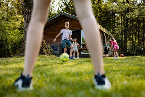 Bambini che giocano a calcio davanti a una tenda safarilodge al Camping De Noetselerberg nei Paesi Bassi.