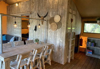 Interior of Glamphuys safari tent at Buitengoed Ruysbos in the Netherlands with rustic wooden furniture.
