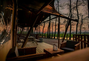 Safari tent Glamphuys at Buitengoed Ruysbos in the Netherlands, sunset view from a furnished outdoor deck.