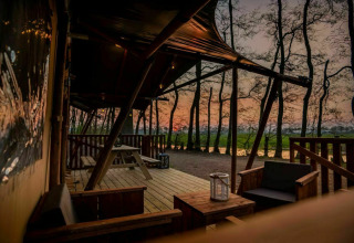 Safaritent Glamphuys bij Buitengoed Ruysbos in Nederland, houten terras met uitzicht bij zonsondergang.