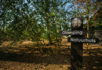 Wegwijzer bij Buitengoed Ruysbos in Nederland toont richting naar glamping en natuurhuis tussen bomen.