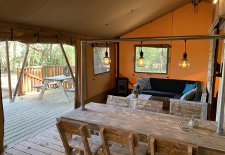 Interieur van safari tent Glamphuys bij Buitengoed Ruysbos in Nederland, met houten meubels en terras.