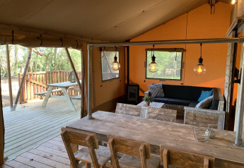 Interieur van safari tent Glamphuys bij Buitengoed Ruysbos in Nederland, met houten meubels en terras.