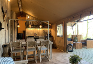 Intérieur de tente safari au Glamphuys, Buitengoed Ruysbos, Pays-Bas, avec meubles rustiques et lumière chaleureuse.