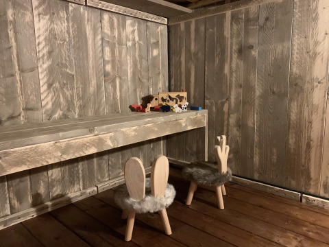 Mesa y sillas de madera con diseño de orejas de conejo en una cabina rústica, juguetes en la mesa.