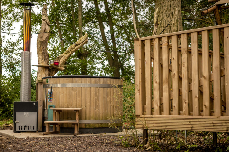 Wood-fired hot tub beside a wooden terrace in the forest at Glamphuys, Buitengoed Ruysbos, Netherlands.