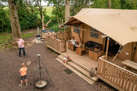 Familie ontspant en speelt buiten bij een safaritent van Glamphuys Ultra Wellness in Nederland.
