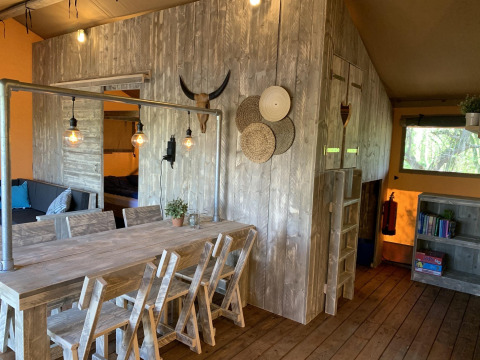 Interior de la tienda safari Glamphuys Ultra Wellness en Buitengoed Ruysbos, Países Bajos, con madera rústica.