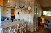 Interiør af safari telt Glamphuys Ultra Wellness på Buitengoed Ruysbos med rustikke træmøbler.