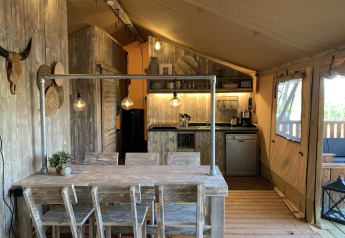 Intérieur de tente safari rustique au Glamphuys Ultra Wellness, Buitengoed Ruysbos, Pays-Bas, avec coin cuisine et salle à manger.