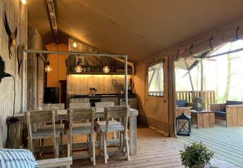 Interior de la tienda safari Glamphuys Ultra Wellness en Buitengoed Ruysbos, Países Bajos, con muebles rústicos.