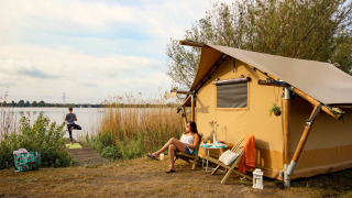 Twee vrouwen ontspannen bij een safaritent aan het water bij Marina Parcs Almere, Nederland.