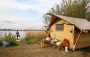 Dos mujeres disfrutan junto a una tienda safari junto al lago en Marina Parcs Almere, Países Bajos.