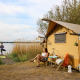 Two women enjoy a lakeside safari tent vacation at Marina Parcs Almere, Netherlands, close to nature.