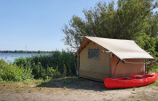 Safari-telt ved Marina Parcs Almere i Holland, ved søbredden, med en rød kano foran teltet.